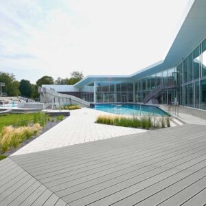 Pilka NaturInForm Compact Massive WPC terasa prie baseino ir modernaus pastato